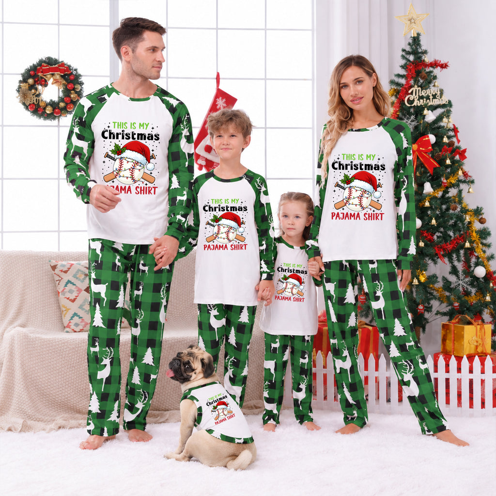 A family of four wearing matching Christmas pajamas stands in a living room with a Christmas tree, wreath, and holiday decorations. The pajamas feature a white front with green raglan sleeves and green plaid pants, printed with cartoon dogs wearing Santa hats and the text 'THIS IS MY Christmas PAMMA SHIRT'.