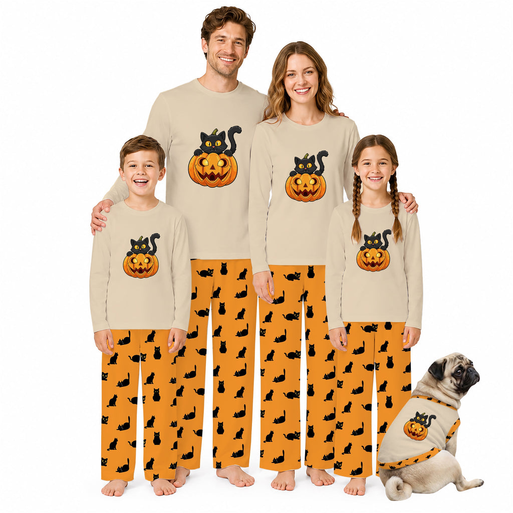 A family of four wearing matching Beige long-sleeve pajamas with orange Halloween-themed graphics, standing barefoot on a White background, with a small dog sitting beside them wearing a matching pajama set.