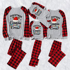 A matching family Christmas cousin crew pajama set laid out on a white textured background, including long-sleeve raglan shirts and matching pants in red and black buffalo plaid with a gray body and 'Christmas Cousin Crew' holiday graphic.