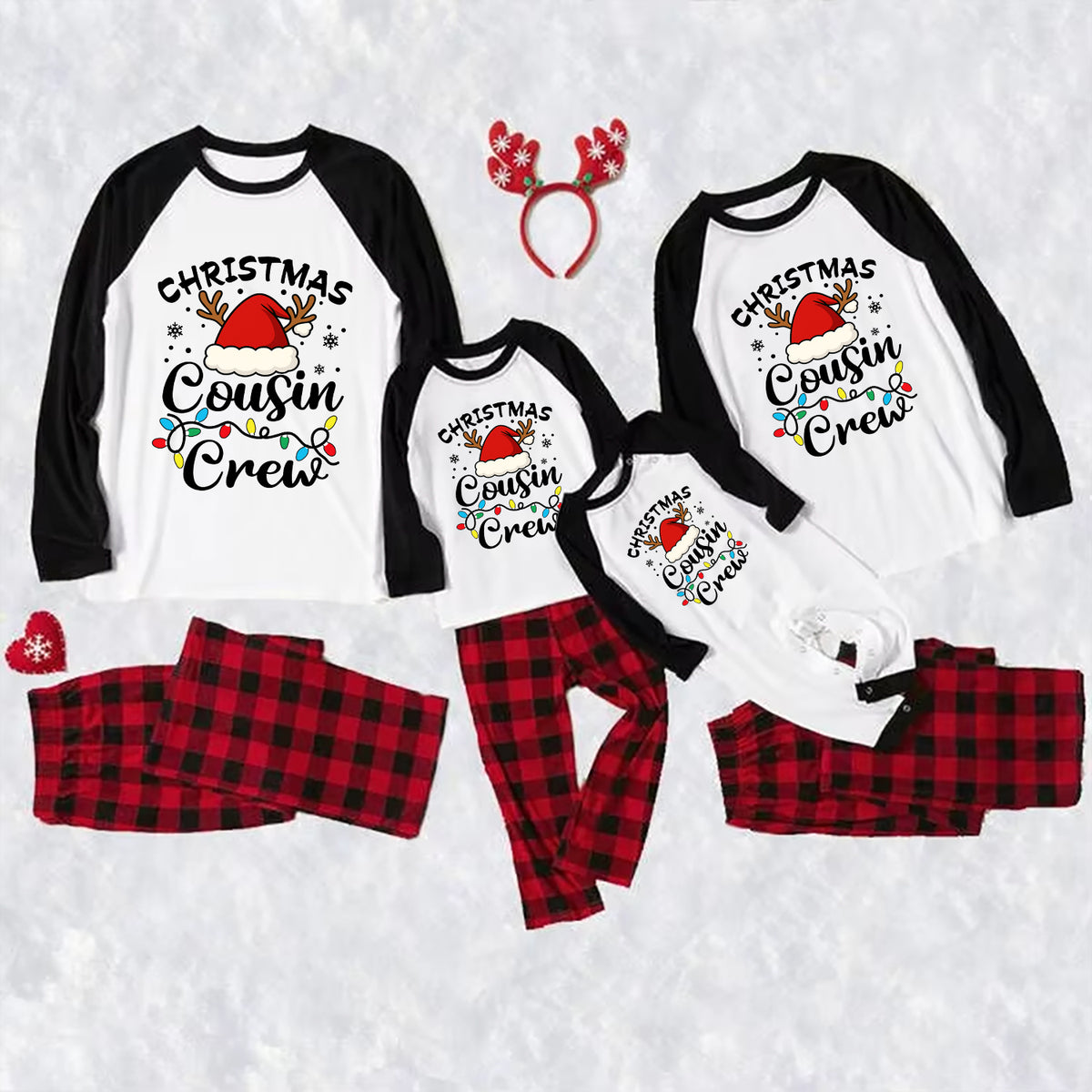 A family Christmas cousin crew pajama set laid out on a white textured background, including four raglan long-sleeve shirts in different sizes with black sleeves and black collar trim, printed with 'Christmas Cousin Crew' and a Santa hat graphic, matching red and black plaid pants, a red snowflake headband, and a red snowflake accessory.