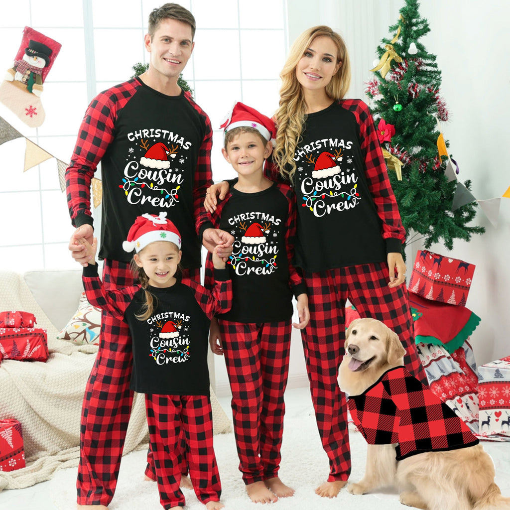 A family of four wearing matching black and red buffalo plaid Christmas pajamas with 'Christmas Cousin Crew' printed on the front, posed in a festive living room with a Christmas tree, wrapped gifts, and a golden retriever dog wearing a matching plaid shirt.