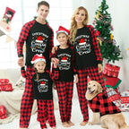 A family of four wearing matching black and red buffalo plaid Christmas pajamas with 'Christmas Cousin Crew' printed on the front, posed in a festive living room with a Christmas tree, wrapped gifts, and a golden retriever dog wearing a matching plaid shirt.