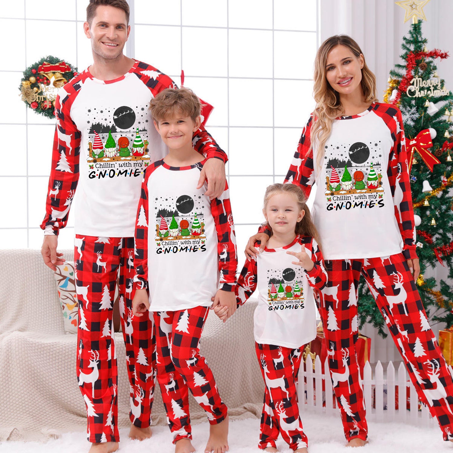 A family of four wearing matching Christmas-themed long-sleeve pajamas with a white front and red-and-black buffalo plaid sleeves and pants. The pajama design features a gnomes graphic with the text 'FIND ME A GNOOME!'.