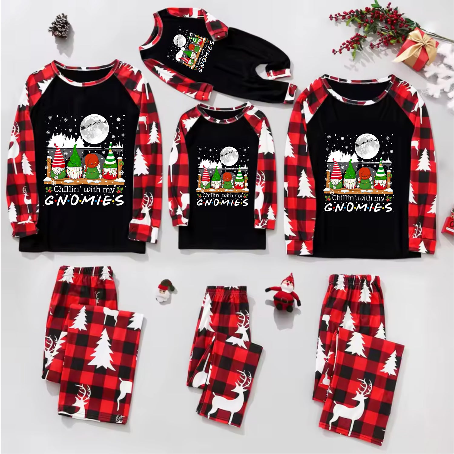 A flat lay of a Christmas-themed pajama set for multiple sizes, featuring long-sleeve raglan shirts with red and black buffalo plaid sleeves and a festive gnome graphic on the front, paired with matching plaid and white reindeer-patterned pants.