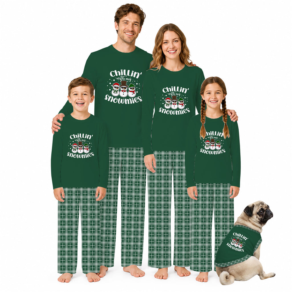 A family of four and a dog wearing matching dark green long-sleeve pajamas with 'Chillin' Snowman' graphics and green plaid pants, posed against a plain white background.