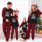 A family of four and a dog wearing matching black and red plaid Christmas pajamas with 'Christmas 2026 Cousin Creep' printed on the front, posed in a festive living room with a Christmas tree and stockings in the background.