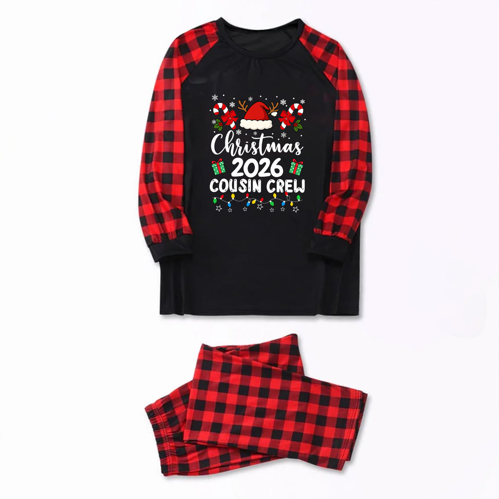 A two-piece holiday pajama set featuring a black long-sleeve top with red and black buffalo plaid raglan sleeves and a festive Christmas 2026 cousin crew graphic, paired with matching red and black buffalo plaid pants, displayed on a clean white background.