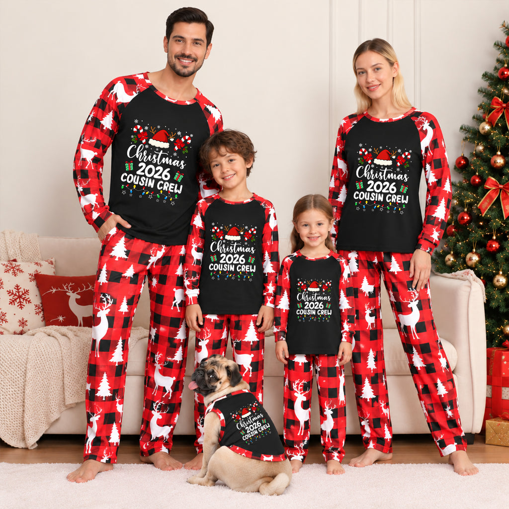 A family of four wearing matching Christmas-themed long-sleeve pajamas stands in a living room with a couch, tree, and dog. The pajamas have a black chest panel with white text reading 'Christmas 2026 Cousin Creep' and a red-and-black buffalo plaid pattern with white reindeer and tree motifs.