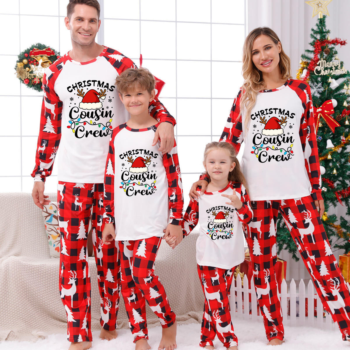A family of four wearing matching Christmas-themed pajamas with the text 'Christmas Cousin/Cousin Crew' on the front, posed in a festive living room with a decorated Christmas tree and holiday wreath.