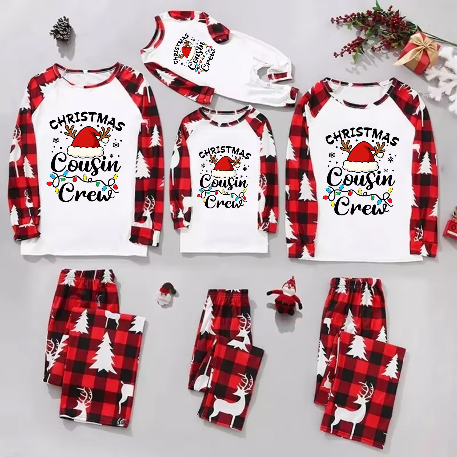 Three matching Christmas cousin crew pajama sets arranged on a light gray background, including long-sleeve raglan shirts and plaid pants in red, black, and white holiday prints. The shirts read 'Christmas Cousin Crew' with a Santa hat and colorful holiday accents, and the pants feature tree and reindeer motifs.
