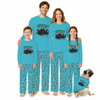 A family of four wearing matching turquoise long-sleeve pajamas with a Christmas tree graphic and multicolor holly-patterned pants, standing barefoot on a white background next to a matching dog shirt with a pug.