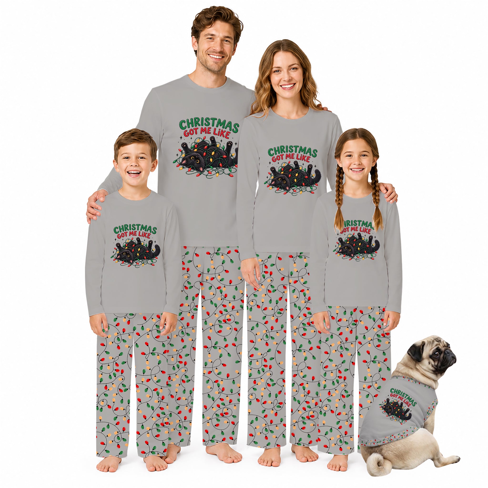 A family of four wearing matching gray long-sleeve pajamas with a Christmas tree graphic and red/green holiday print on the pants, standing together on a white background with a small matching dog at their side.