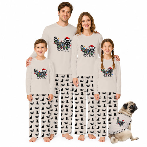 A family of four wearing matching Christmas-themed pajamas stands together on a white background, with a small dog sitting at their right. The pajamas are light beige long-sleeve tops with a colorful raccoon graphic wearing a Santa hat, paired with black-and-white cat-print pants.