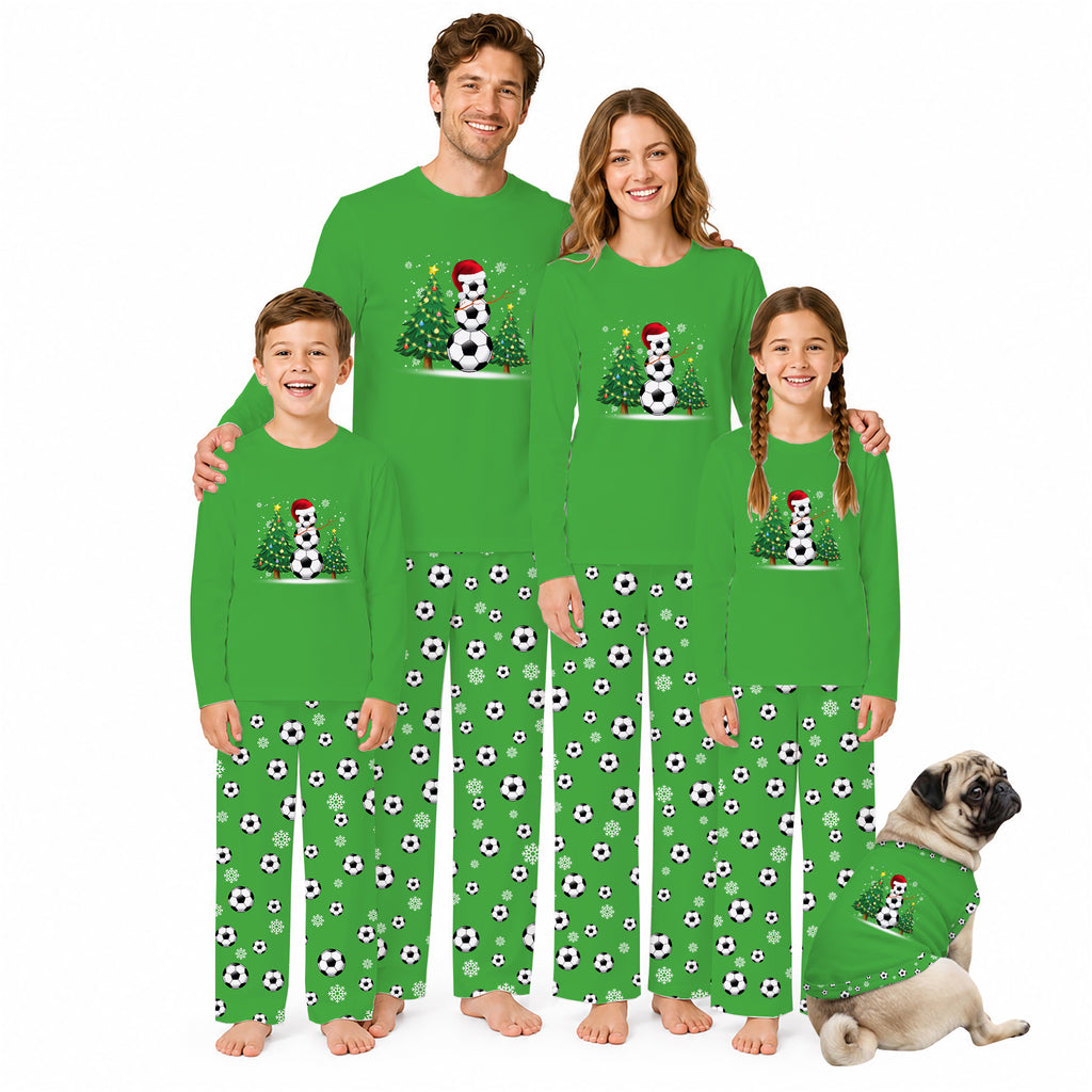 A family of four wearing matching bright green long-sleeve pajamas with a soccer-themed snowman graphic and black-and-white soccer ball prints on the pants, posed against a white background with a small dog in matching pajamas.