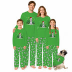 A family of four wearing matching bright green long-sleeve pajamas with a soccer-themed snowman graphic and black-and-white soccer ball prints on the pants, posed against a white background with a small dog in matching pajamas.