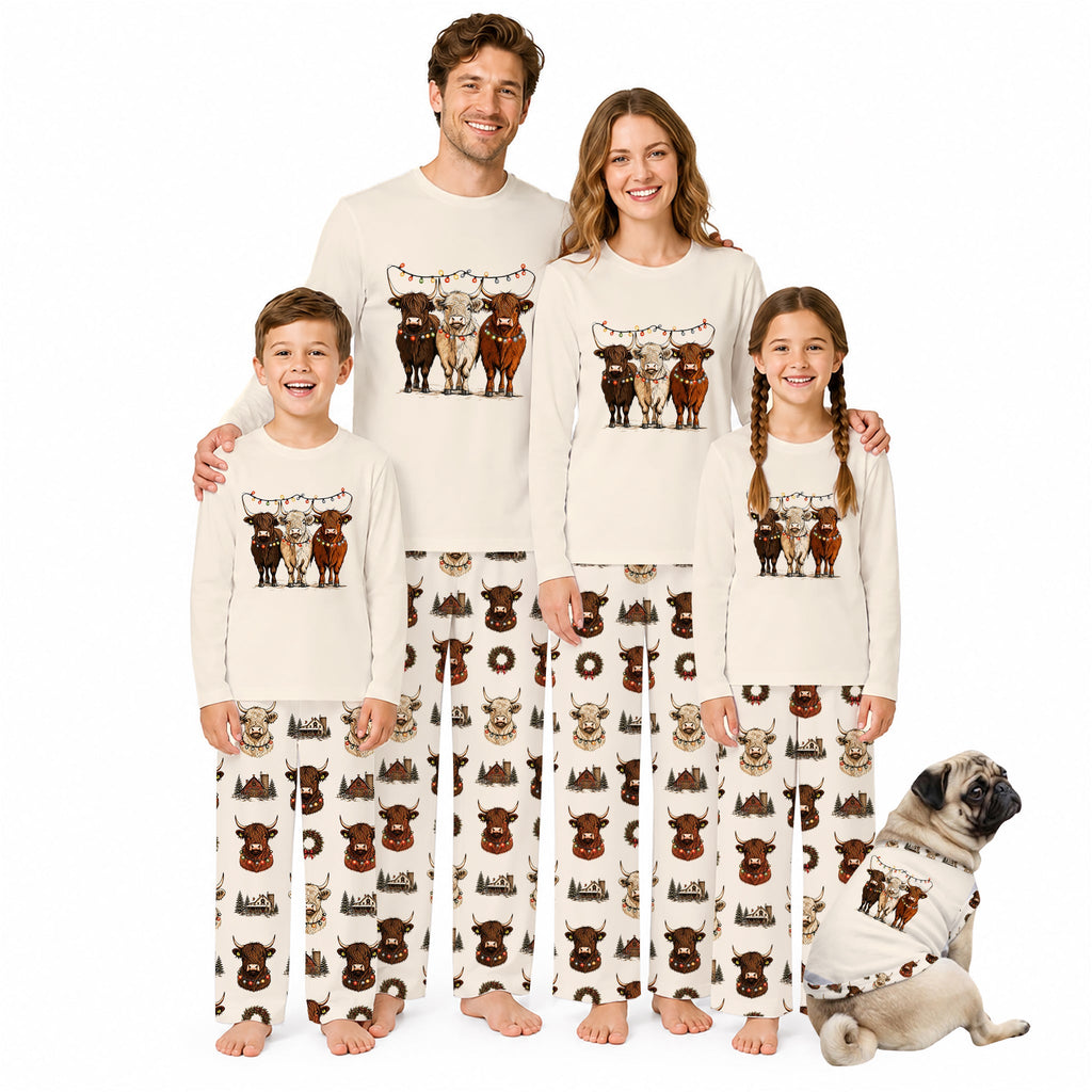 A family of four wearing matching Christmas-themed pajamas stands together on a White background, with a small dog in a matching pajama set sitting beside them. The pajamas are Cream-coloRed with a graphic of four cows at the top and a repeating pattern of brown cows and holiday motifs below.