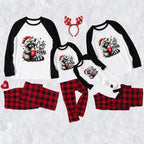 Three matching family Christmas raglan pajamas laid out on a white textured background, including large, medium, and small long-sleeve shirts with black sleeves and a raccoon graphic that reads 'Cute But Feral,' plus red-and-black plaid pants. A red reindeer antler headband and small red heart accessory are also included.