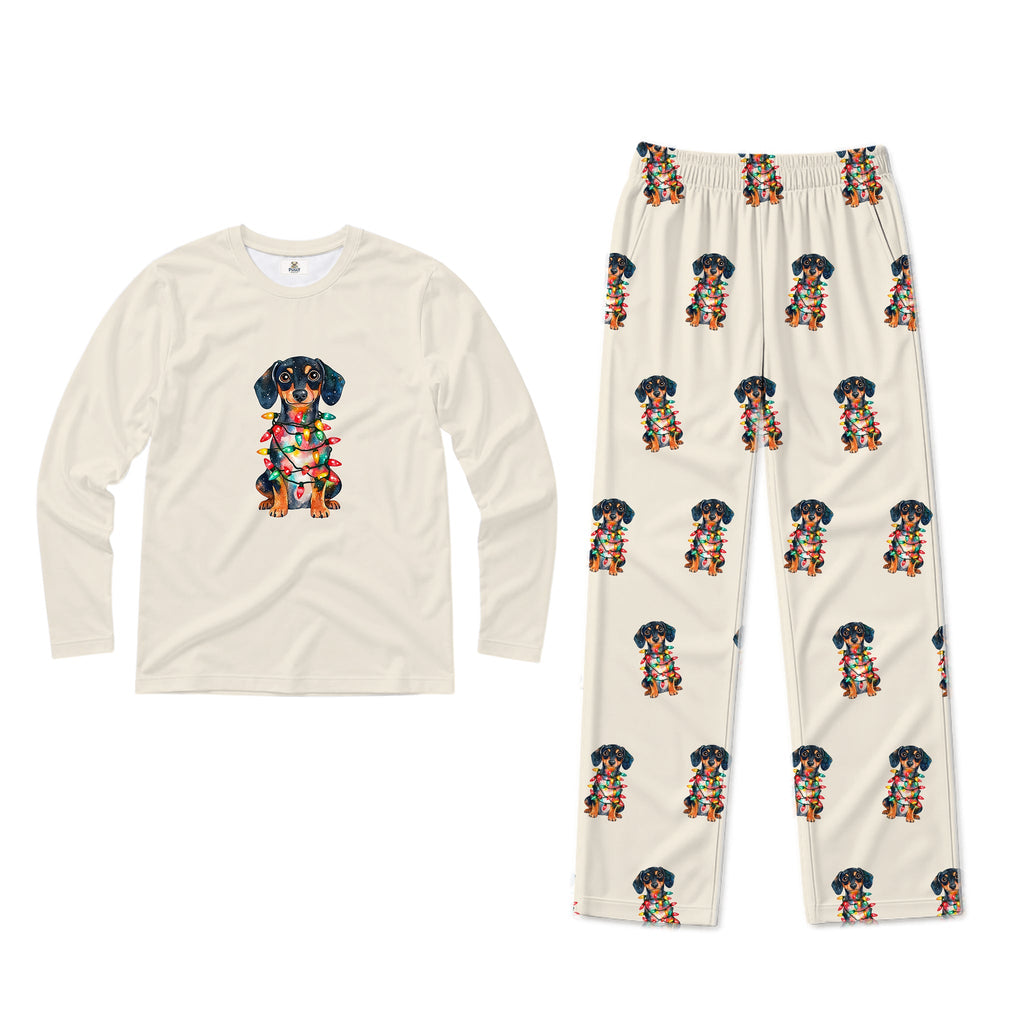 A two-piece pajama set on a plain White background, featuring a Cream long-sleeve shirt with a colorful dachshund graphic on the chest and matching Cream pants with an all-over dachshund print.