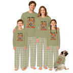 A family of four wearing matching sage green Thanksgiving-themed pajamas with a turkey graphic and plaid pants, standing barefoot on a white background next to a small matching dog.