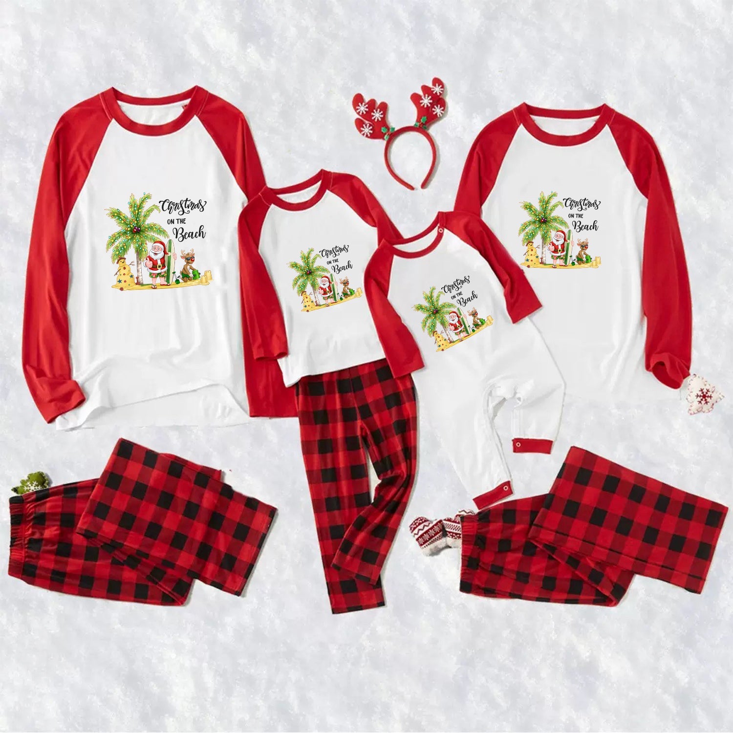A matching family Christmas pajama set laid flat on a White textuRed background, including three raglan long-sleeve tops in Red and White with a tropical Santa graphic, three matching pants in Red buffalo plaid, a Red reindeer antler headband, and small Red-and-White booties.