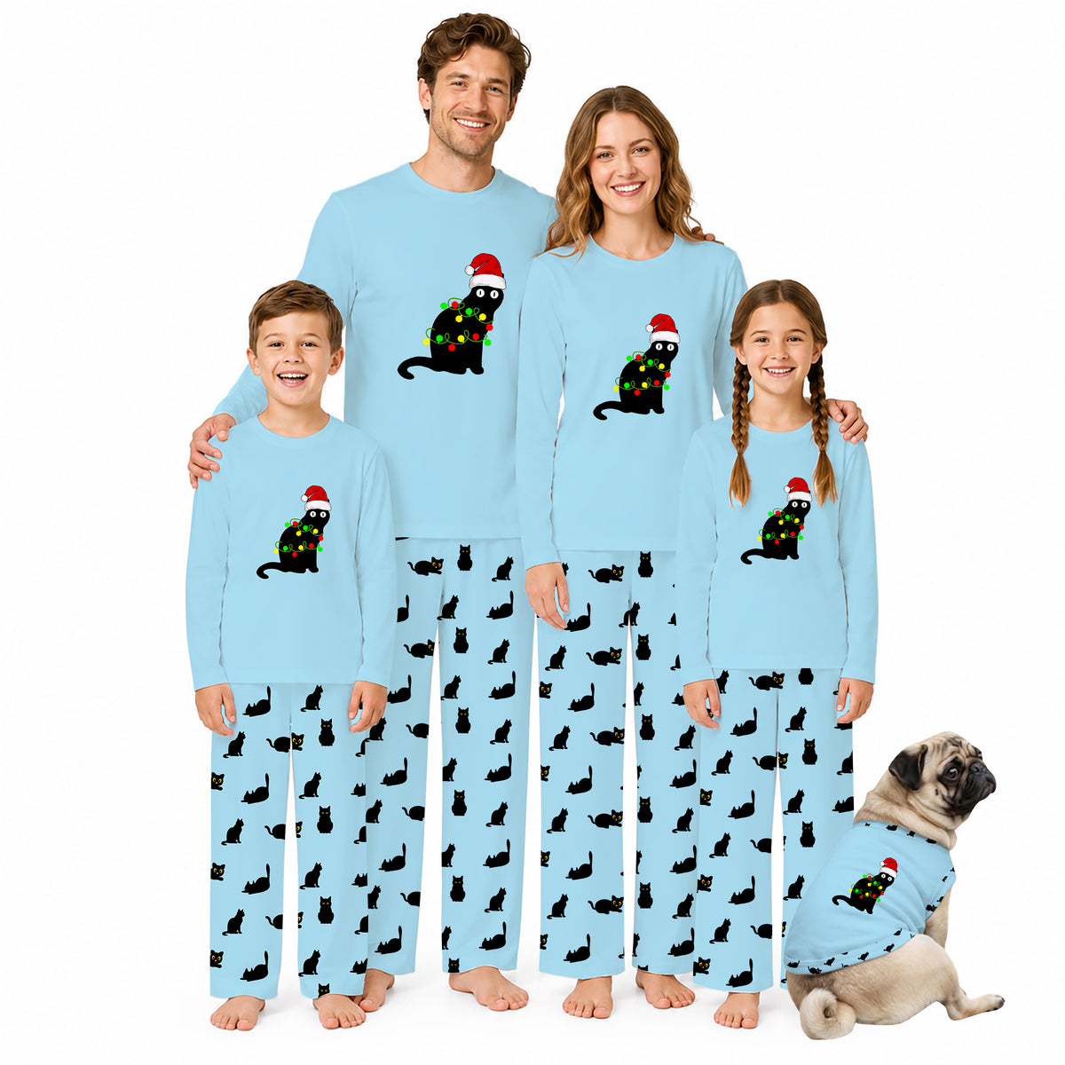 A family of five wearing matching light blue Christmas-themed pajamas with a black cat wearing a Santa hat and green/yellow holiday accents, standing against a white background with a small matching dog at their side.