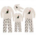 Three sizes of matching family Christmas pajamas shown on a white background, featuring a beige long-sleeve top with a black cat wearing a green Christmas tree and red Santa hat, paired with beige pants patterned with small black cat silhouettes.