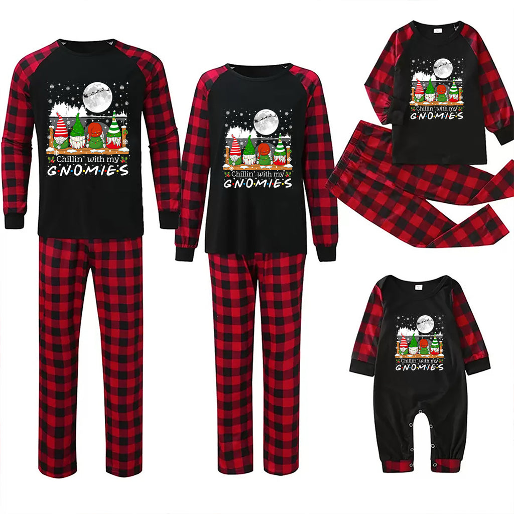 Three sizes of matching Christmas pajama sets shown on a white background: a large adult set, a medium set, and a baby set. Each set includes a black long-sleeve top with red buffalo plaid sleeves and a festive gnome graphic with the text 'MERRY CHRISTMAS ALL THE TIME GNOMIES' on the chest, paired with red and black buffalo plaid pajama pants.