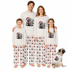 A family of four wearing matching Christmas-themed long-sleeve pajamas and matching pants, standing together on a white background with a small dog wearing a matching pajama shirt at the lower right. The pajamas are off-white with a black and red raccoon graphic and the text 'Cute Feral' on the chest, and the pants have an all-over print of the raccoon graphic.