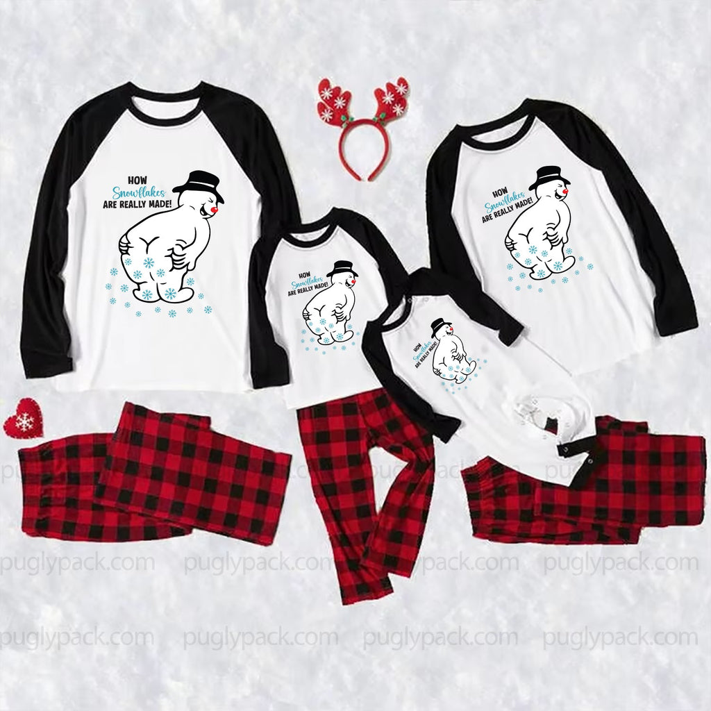 A coordinated family Christmas pajama set laid out on a White textuRed background, including three Black-and-White raglan long-sleeve shirts with polar bear graphics and text, matching Red-and-Black plaid pants, a Red reindeer antler headband, and small Red holiday accents.