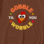A close-up of a brown garment featuring a colorful graphic print with the text 'GOBBLE TIL YOU WOBBLE' and a cartoon turkey face in the center.