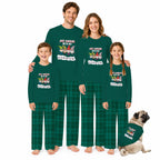 A family of four wearing matching dark Green long-sleeve pajamas with a gnome graphic and the text 'JUST HANGING WITH MY Gnomes' stands barefoot against a White background, with a small pug dog wearing a matching pajama set beside them.