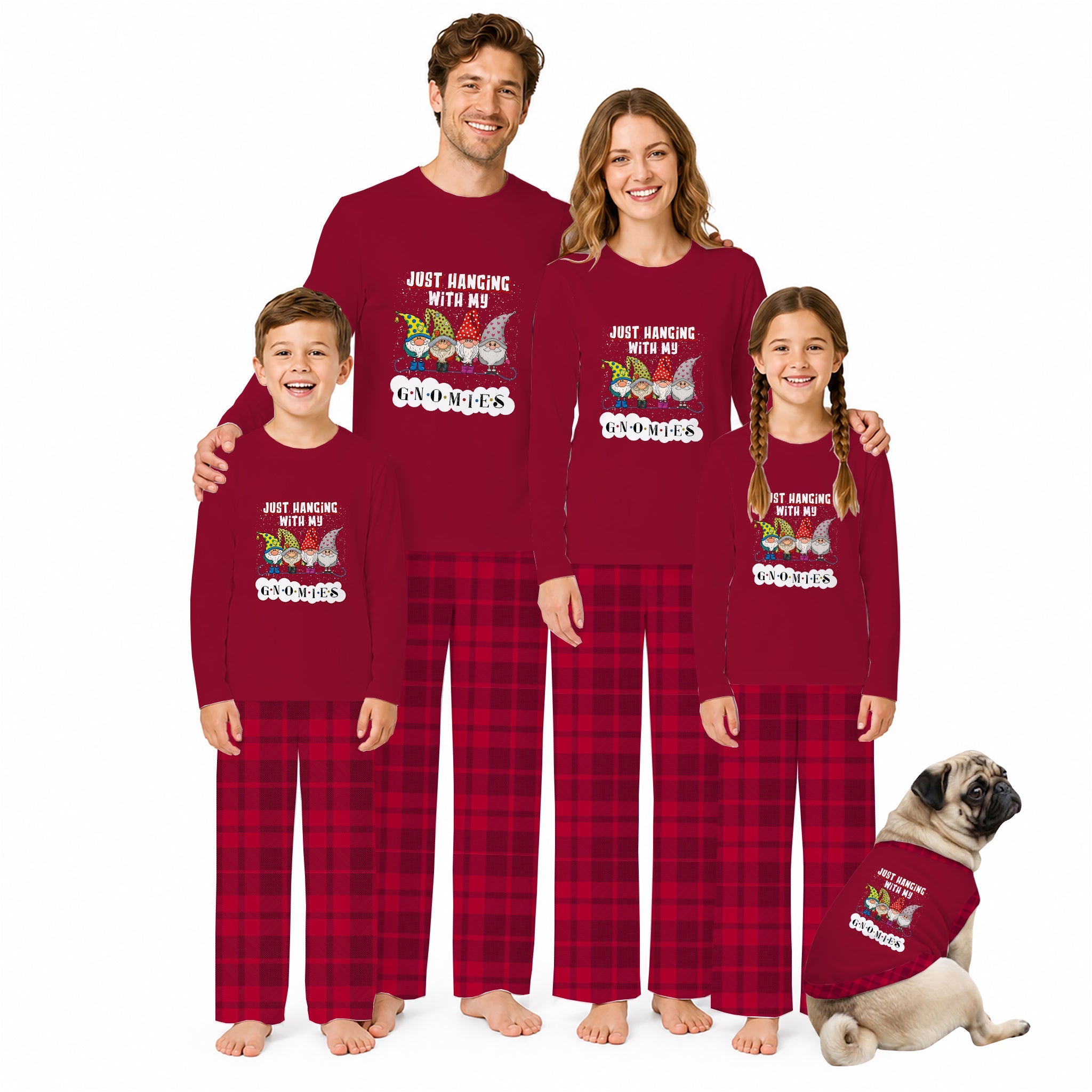 A family of four and a dog wearing matching holiday pajamas with a Red graphic shirt and Red plaid pants, standing and sitting against a plain White background.