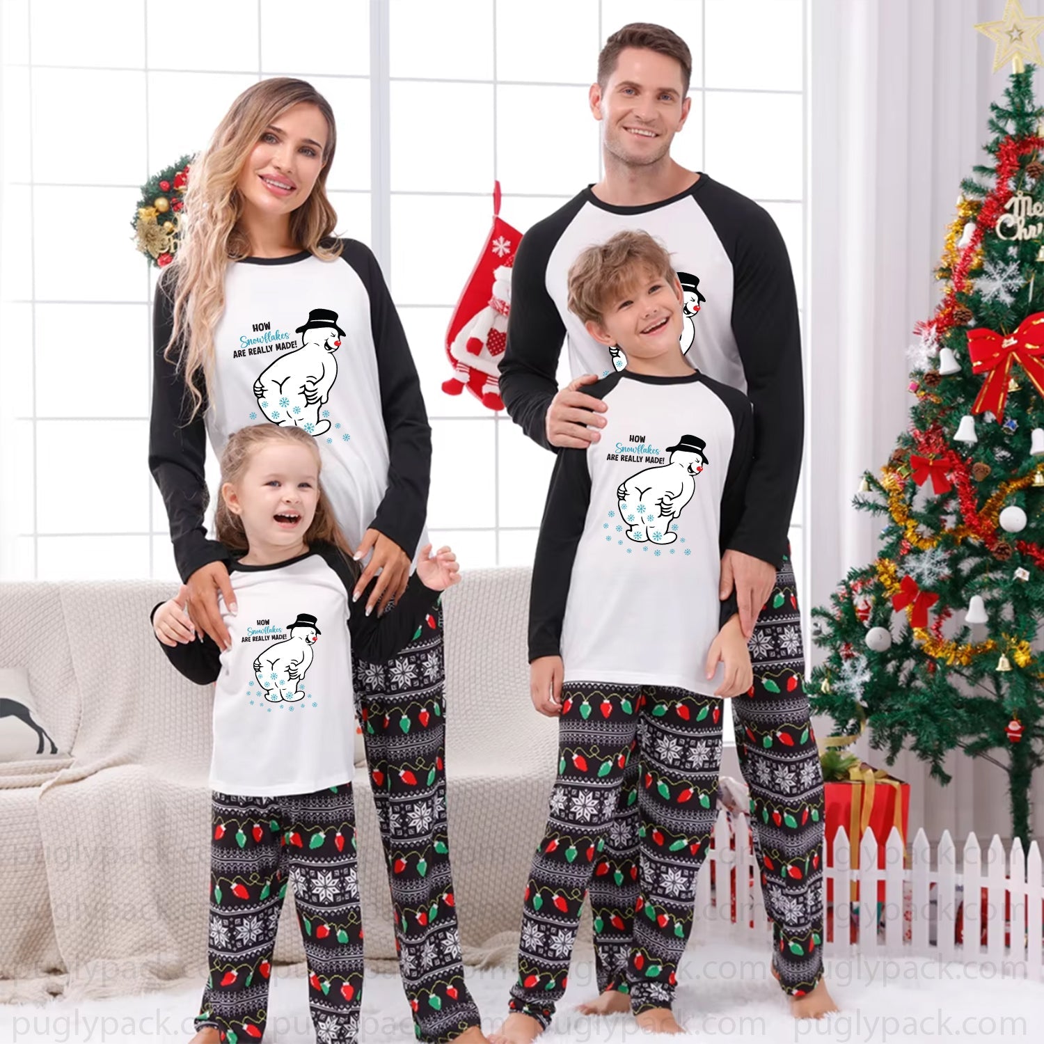 A family of four wearing matching Christmas pajamas stands together in a living room setting with a decorated Christmas tree, couch, and holiday decorations. The pajamas feature a White front with Black long sleeves and a cartoon snowman graphic, paiRed with Black and White patterned pants.
