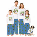 A family of four wearing matching custom-printed white t-shirts and blue pajama pants with a palm tree pattern, standing together on a white background with a small matching dog shirt and a pug dog sitting at their right.
