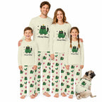 A family of four and a dog wearing matching Christmas-themed pajamas against a plain White background. The pajamas are Cream-coloRed with a Green cat graphic and the text 'Merry Catmas', and the pants feature a pattern of Green cats, paw prints, and Red snowflakes.
