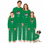 A family of four wearing matching green long-sleeve pajamas with a personalized cartoon graphic and the name 'Jack' on the chest, standing barefoot against a white background. A small pug dog sits to the right wearing a matching pajama set.
