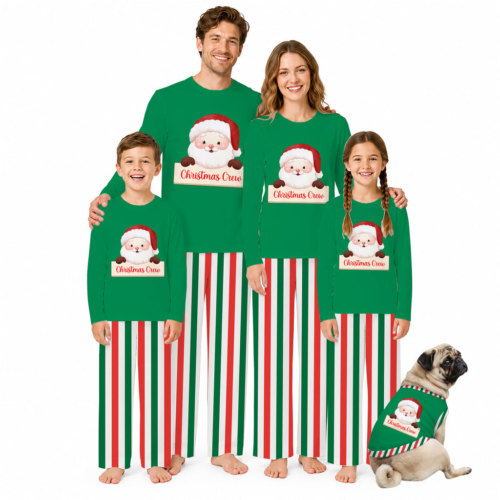 A family of five wearing matching Christmas-themed long-sleeve pajamas stands together on a white studio background, with a small dog wearing a matching pajama set beside them. The pajamas are bright green with red and white vertical stripes and a Santa Claus graphic with a personalized name label.