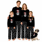 A family of four wearing matching black long-sleeve pajamas with a Santa-themed skull graphic and the name 'Alex' printed on the chest, standing against a white background. A small pug dog sits to the right wearing a matching pajama set.