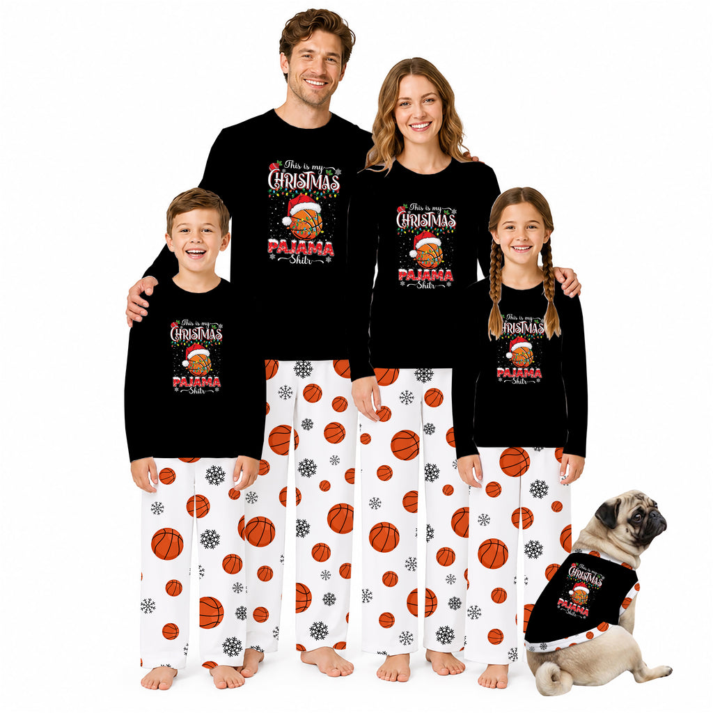 A family of four wearing matching black Christmas pajama tops and white pajama pants with orange basketball prints, standing together on a white background. A small pug dog sits at their right wearing a matching pajama set.